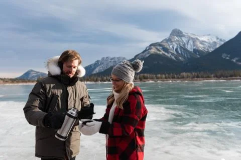 Couple taking coffee while standing in snowy landscape Stock Photos