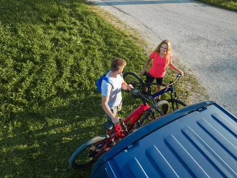 Couple taking down electric mountain bikes from the bike rack on a van Stock Photos