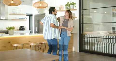 Couple taking hands and dancing near kitchen island, expressing affection, Stock Footage 338437132