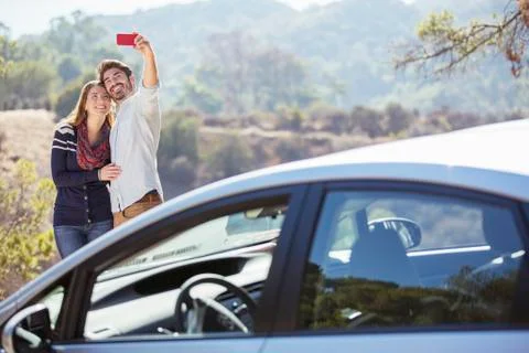 Couple taking self-portrait with cell phone outside car Stock Photos