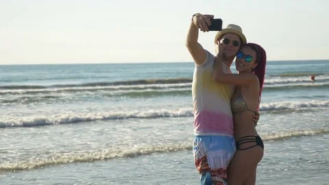 Couple taking selfie and having fun on the shore of a sandy beach Stock Footage 71311318