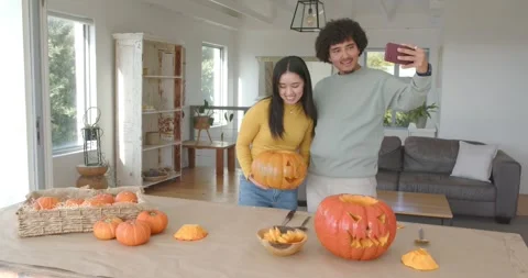Couple taking selfie, placing pumpkin, checking phone, discussing halloween Stock Footage 346709494