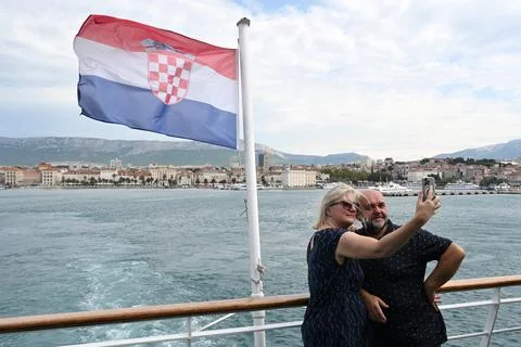 A couple taking a selfie at the Split bay from the ferry.Croatian Flag. Stock Photos