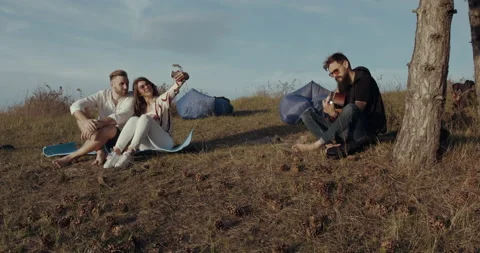 A couple taking a selfie while their friend is playing guitar Stock Footage 134574035
