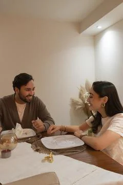 Couple talking during a romantic dinner at home with wine glasses and an eleg Stock Photos