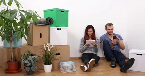 Couple Talking Planning Use Digital Tablet and Mobile Phone New Home Apartment Stock Footage 77064904