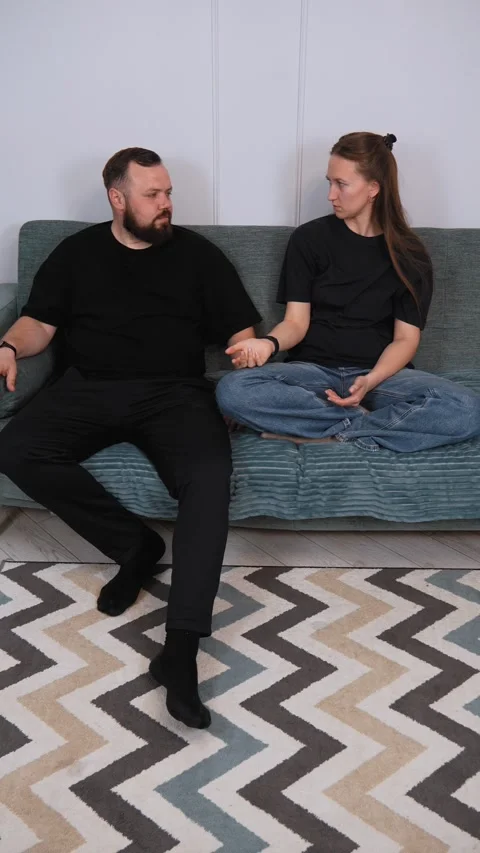 Couple talking on sofa: resolving conflict through communication Vidéo 317444353