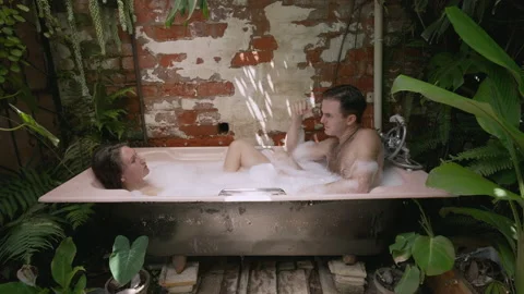 A couple talking while in an outside bath filled with bubble foam. Video stock 170433122