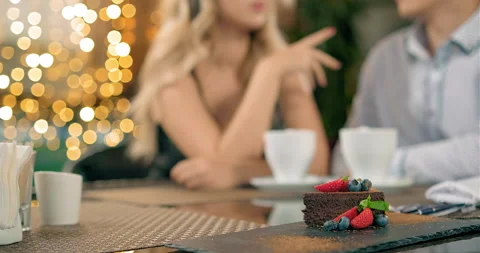 Couple talks at table focus on chocolate cake with berries Stock Footage 142508090