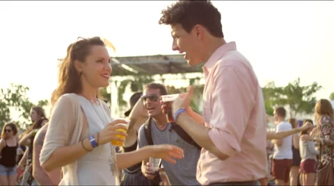 Couple talks while holding drinks at concert Stock Footage 63084514