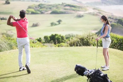Couple teeing off on golf course Fotos de archivo