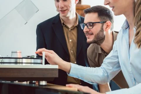 Couple testing a Hi-Fi system in the store with the salesman explaining 스톡 사진