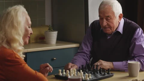 Couple in their 70s playing chess in the kitchen, celebrating with a high five Stock Footage 337652667