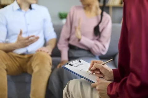 Couple in therapy session with counselor taking notes during relationship Stock Photos