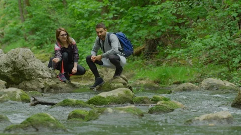 Couple throwing rocks into a river Stock Footage 99963027