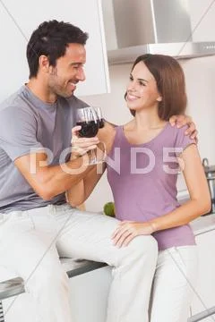 Couple toasting with arms crossed with a glass of wine Stock Photos