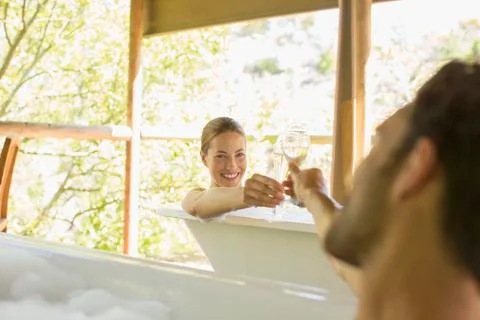 Couple toasting each other in bubble baths Stock Photos