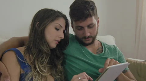 Couple touching the tablet to watch shows and movies on the Internet Video stock 59330119