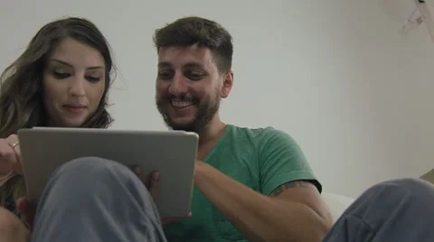 Couple touching the tablet to watch shows and movies on the Internet Video stock 59330539