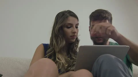 Couple touching the tablet to watch shows and movies on the Internet Video stock 59330545