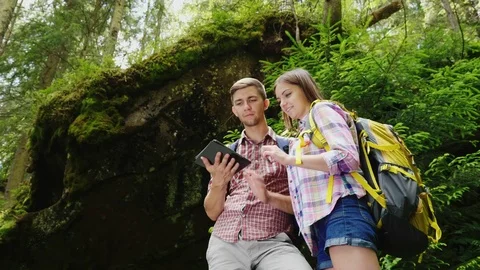 Couple of tourists with backpacks enjoy a tablet on a trip. Navigation and Stock Footage