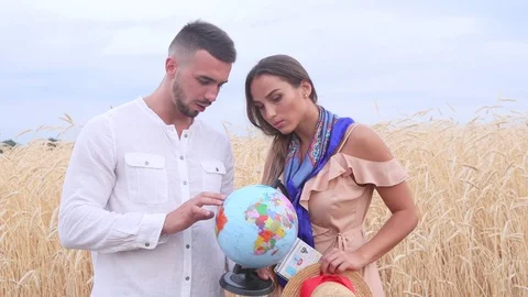 A couple of tourists looking at the globe and choosing where to go 動画素材 77799387