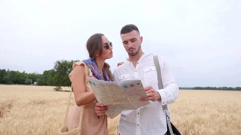 Couple of tourists looking at the map against the background of wheat Stock Footage 77797612
