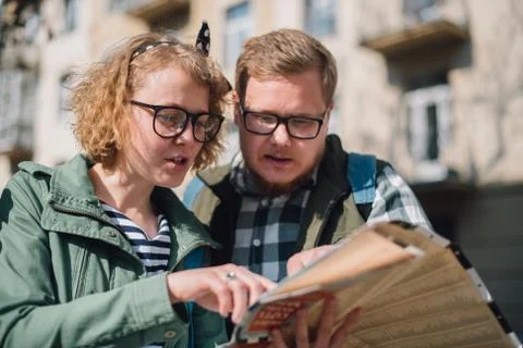 A couple of tourists with a map in their hands are walking around the city Stock Photos