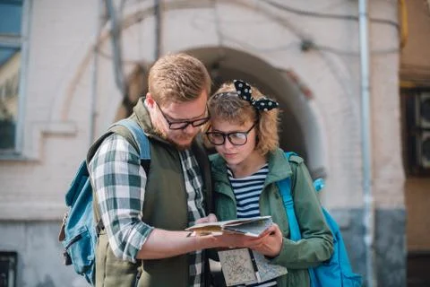 A couple of tourists with a map in their hands are walking around the city 写真素材