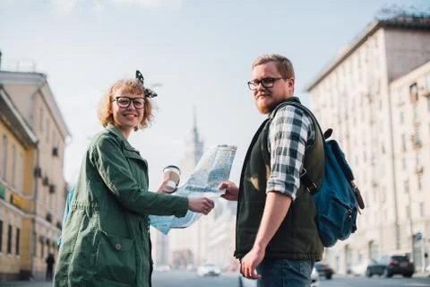 A couple of tourists with a map in their hands are walking around the city 写真素材