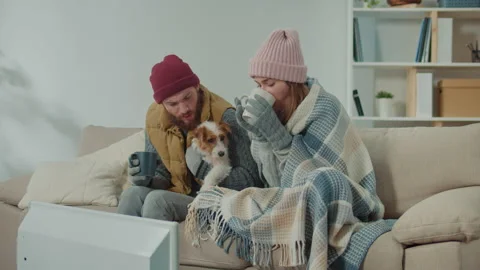 A couple tries to warm up with tea in a cold room with no central heating. Stock Footage 224076955
