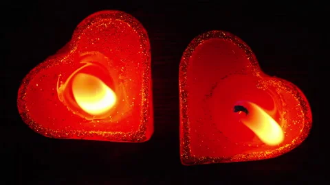 Couple of two candles in the heart shape lighting together on dark wooden table Stock Footage 145976567