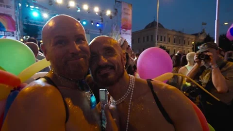 Couple of two gay men is posing cheek to cheek in the middle of the crowd.MOV 스톡 동영상 279134963