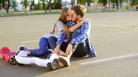 Couple with two hover boards relaxing and kissing Stock Footage 74691432