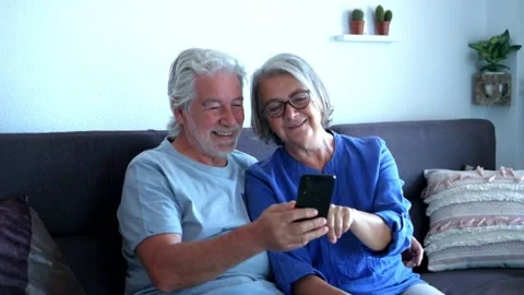 Couple of two seniors using and looking at the same phone having fun and laughin 動画素材 135683138
