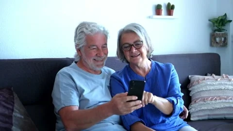 Couple of two seniors using and looking at the same phone having fun and laughin Stock Footage 135683338