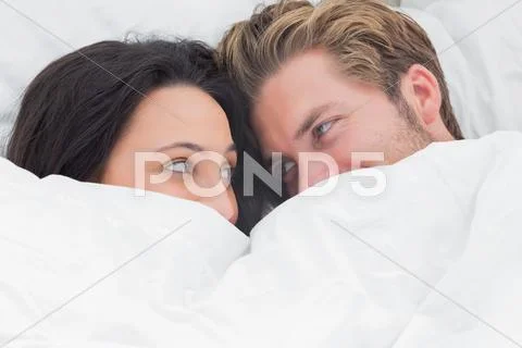 Couple under the duvet looking at each other Stock Photos