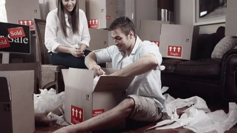 Couple unpacking boxes and organizing/ arranging  placement for their stuff for Stock Footage 199631318