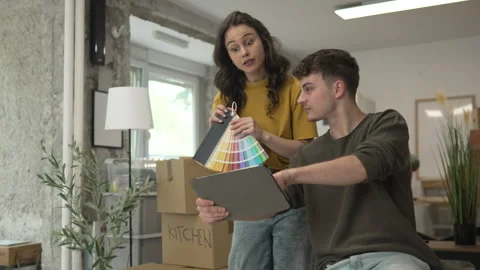 Couple use tablet and color palette to choose color for paint wall Stock Footage 320645346