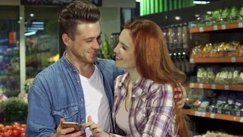 Couple uses smartphone at the hypermarket Stock Footage 76684713