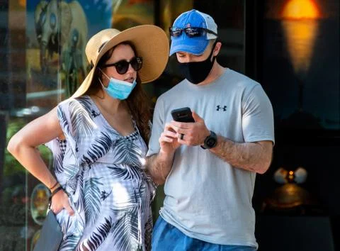 Couple Uses Smartphone While Standing on Pedestrian-Only Street During Pandemic Stock Photos
