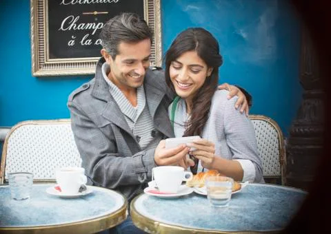 Couple using cell phone at sidewalk cafe, Paris, France Stock-Fotos