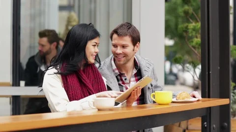 Couple using electronic tablet while sitting outside café Stock Footage 120949008