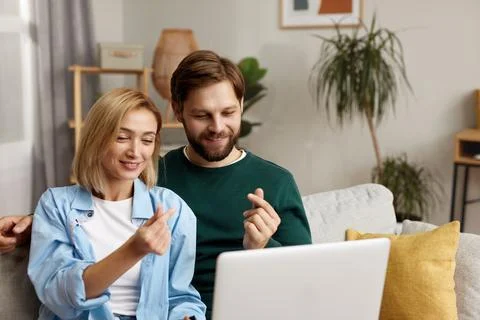 Couple Using Laptop Computer, While Sitting On The Living Room Stock Photos
