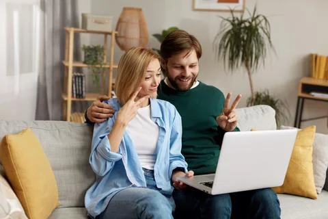 Couple Using Laptop Computer, While Sitting On The Living Room Stock Photos