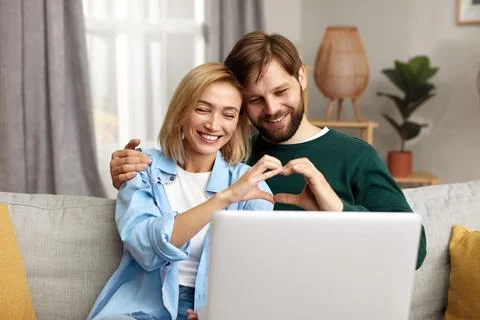 Couple Using Laptop Computer, While Sitting On The Living Room Foto stock