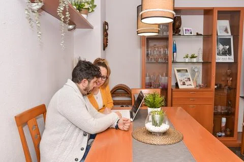 Couple using laptop at home browsing internet in dining room Stock Photos