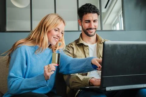 Couple using a laptop to make an online purchase with a credit card, smiling Stock Photos