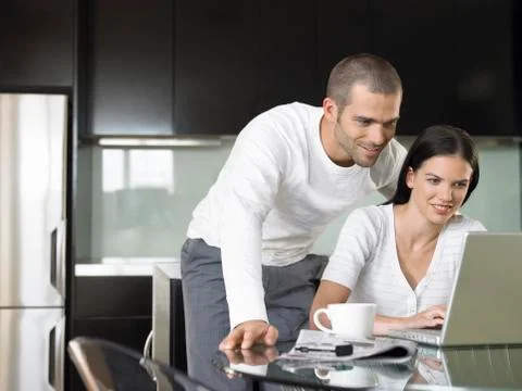 Couple Using Laptop In Modern Kitchen Stock Photos