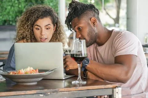 Couple using a laptop while having lunch together. Stock Photos